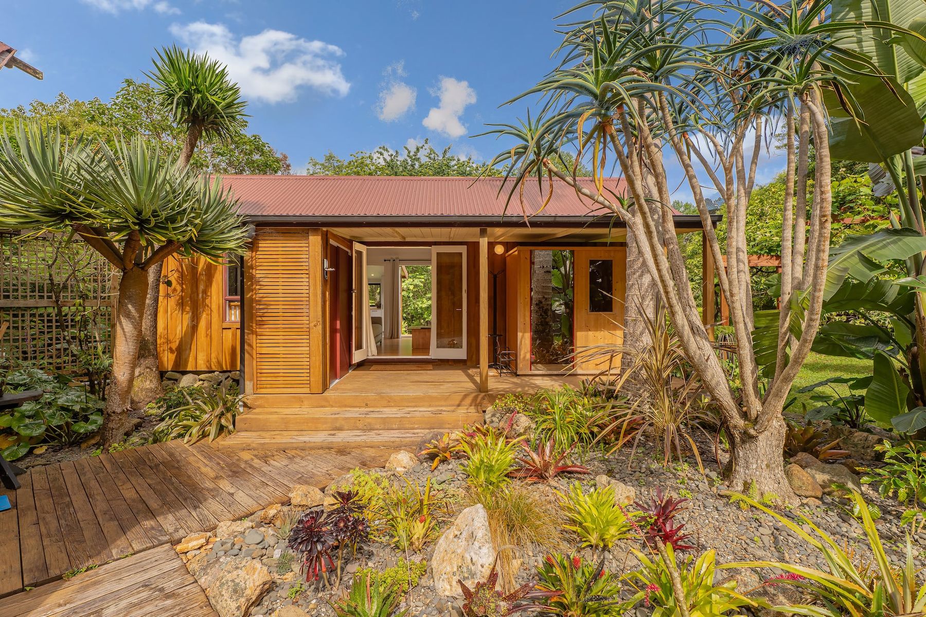 The cottage's timber front and deck among subtropical garden